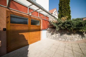 Garážová vrata dvoukřídlá zateplená s celoprosklenou horní částí.